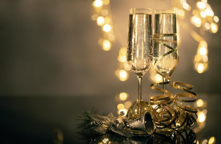 prikaz dve čaše sa šampanjcem i novogodišnjom dekoracijom na stolu