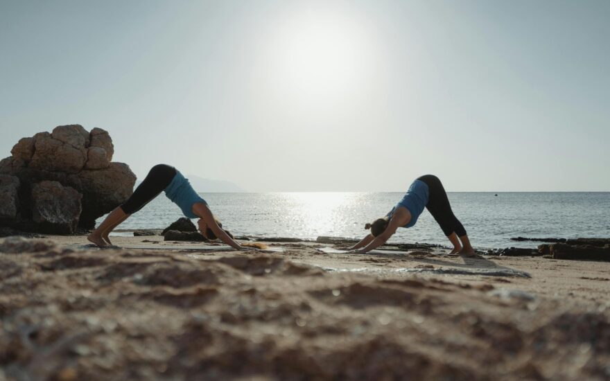 Dve žene rade vežbe na plaži.