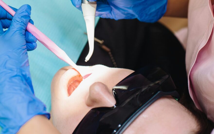 Zubarka radi zub pacijentu instrumentima.