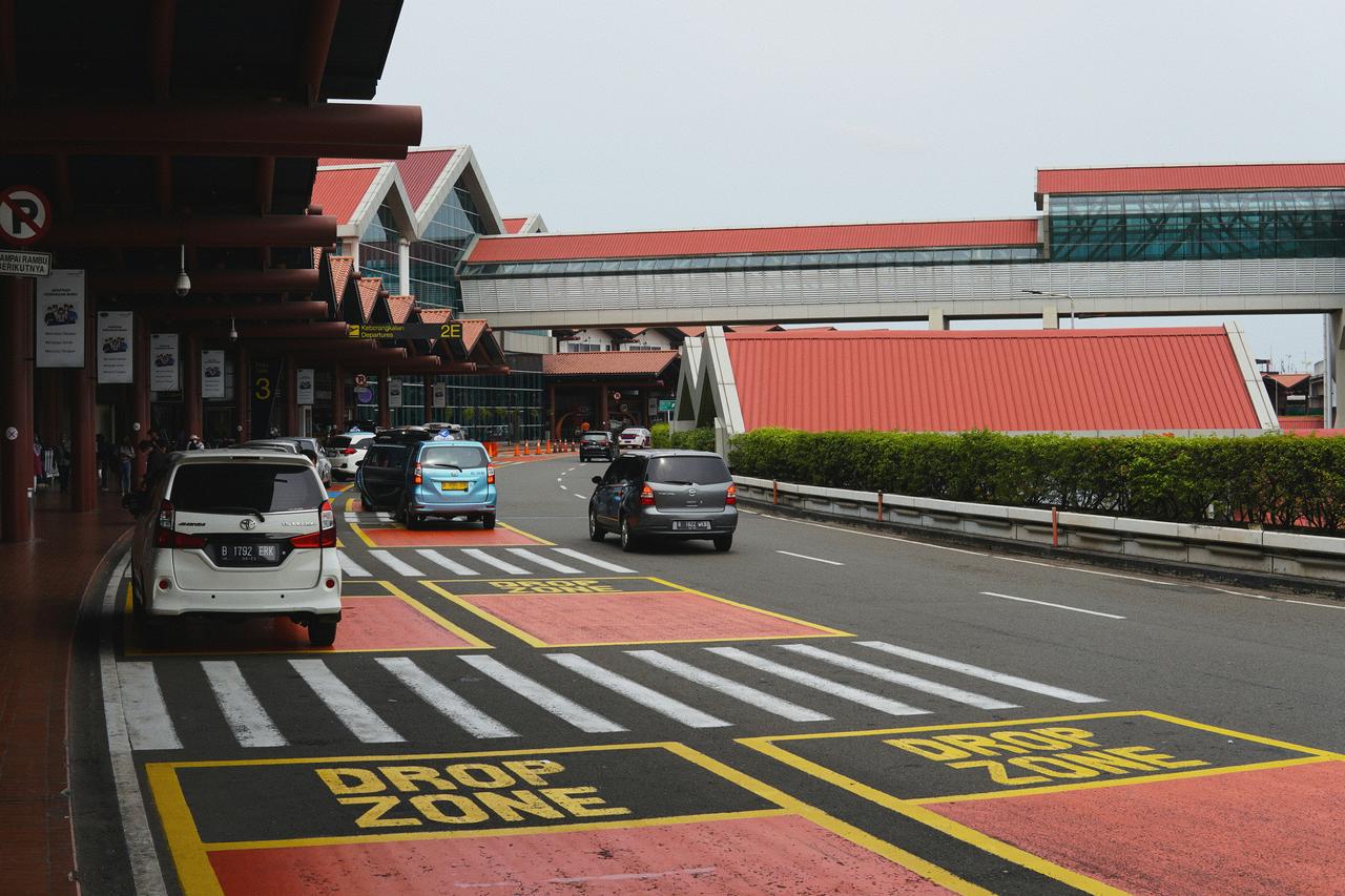 Automobili u zoni iskrcavanja ispred aerodromske zgrade pored pešačkog prelaza