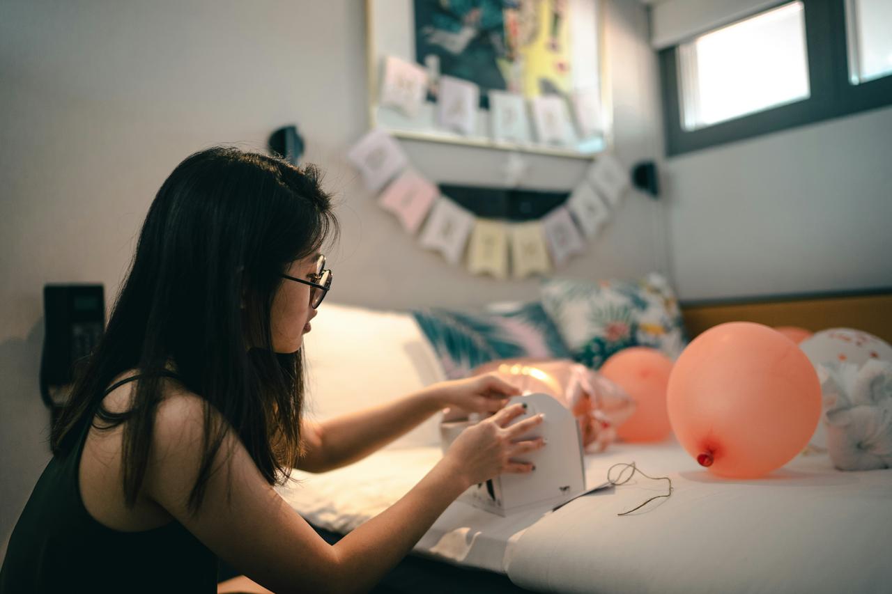 Žena sedi na krevetu i naduvava balone.