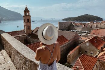 Žena gleda na more sa tvrđave u starom morskom gradu