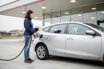 Žena toči gorivo u srebrni automobil na benzinskoj pumpi